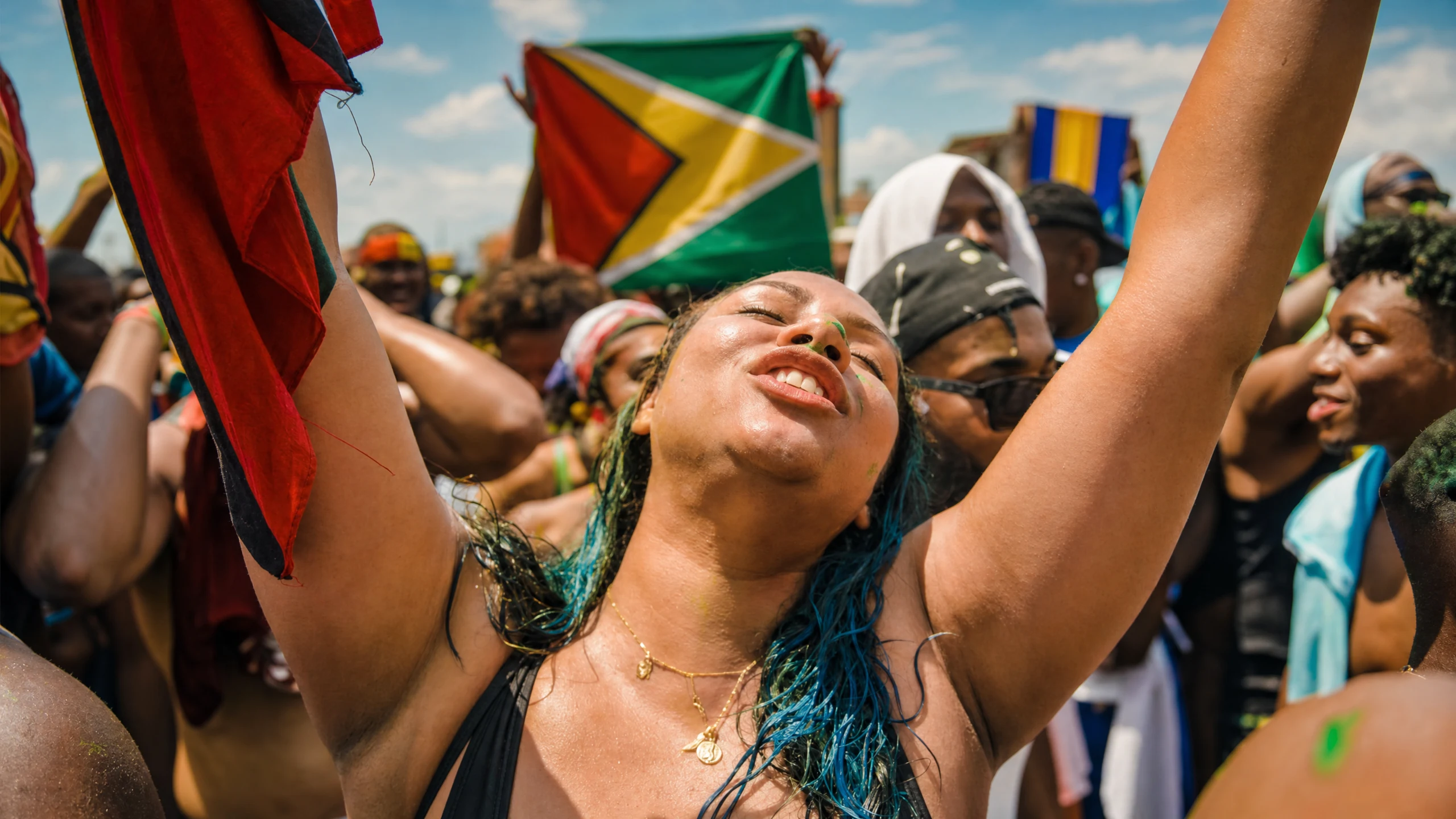 Festival crowd celebrating beneath the Guyana flag