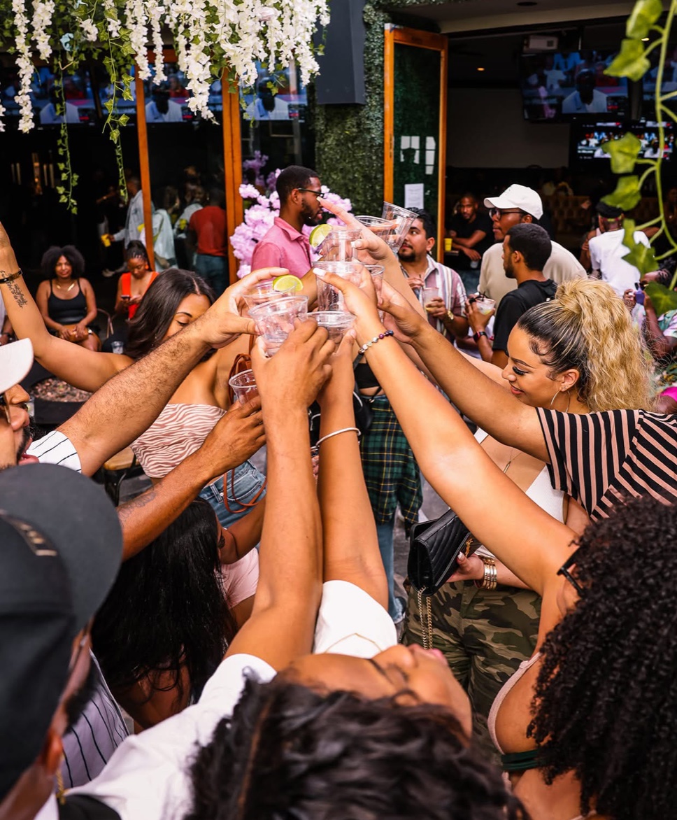 A crowd raising drinks together in a packed outdoor venue.