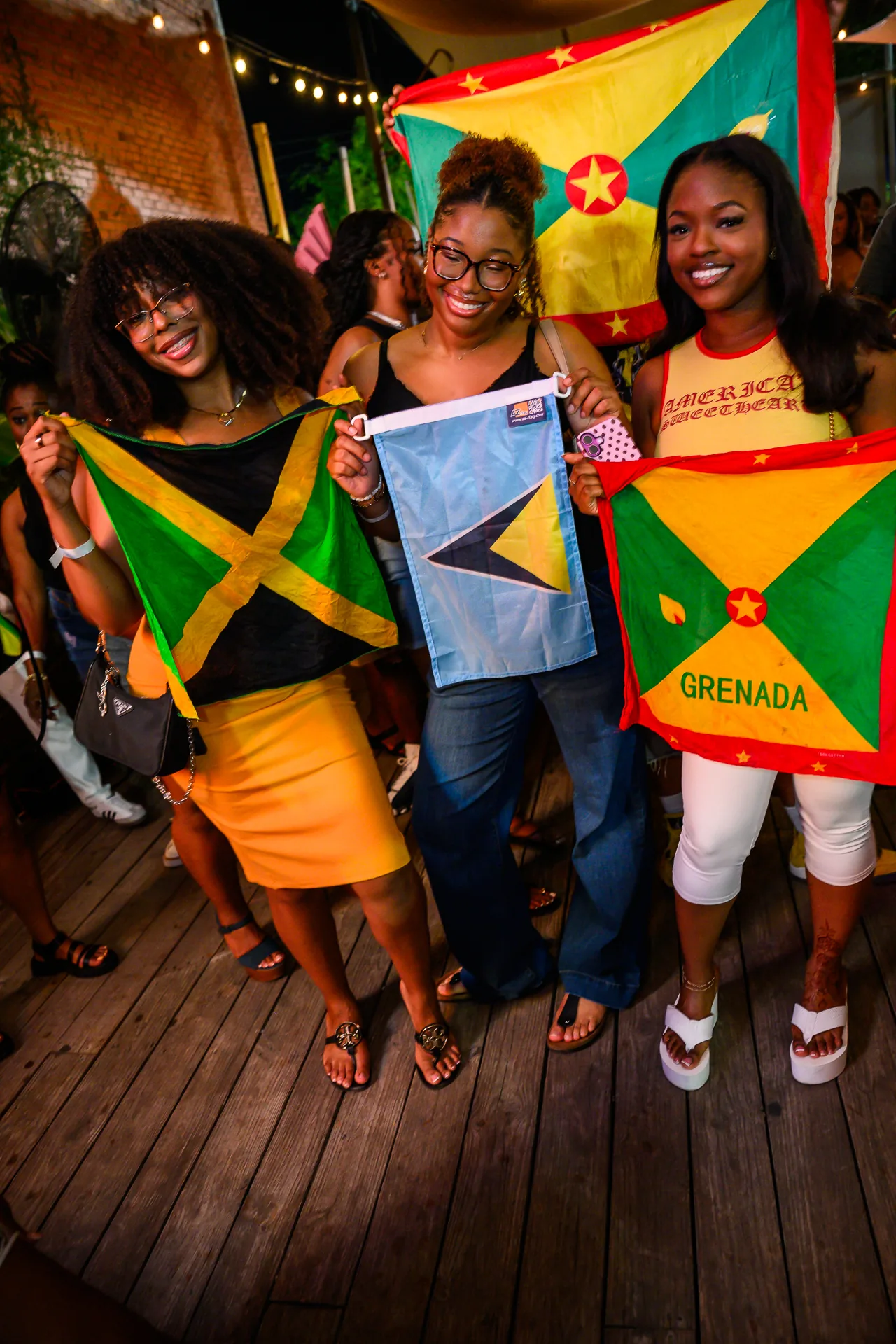 Friends celebrating with Jamaican, Saint Lucian, and Grenadian flags at Culture & Tings.